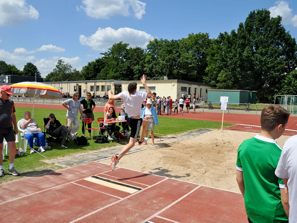 Weitsprung vor der Zuschauergruppe.